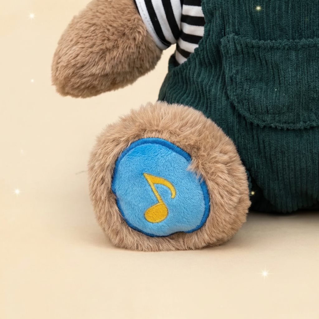 A Christian plush toy teddy bear or stuffed animal shown in a close-up, featuring a brown fuzzy body, dark green corduroy overalls, a black-and-white striped shirt sleeve, and a round blue patch on the paw with a yellow musical note.